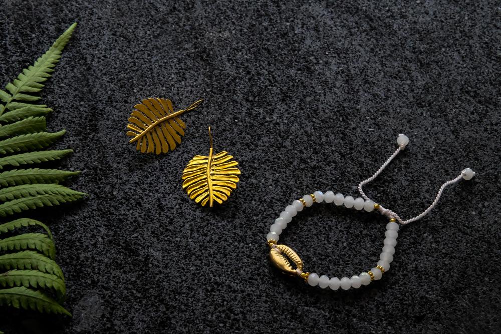 
                  
                    Load image into Gallery viewer, monstera dangle earrings golden boho tropical jewellery and cowrie shell ritual bracelet
                  
                
